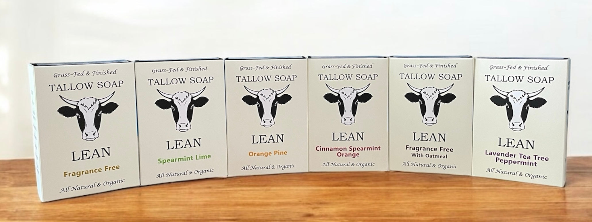 Row of Tallow Soap boxes with cow illustrations on a wooden surface